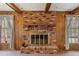 Close-up of a brick fireplace with a wooden mantel, set in a wood-paneled room with natural light at 401 Joyce Rd, Hillsborough, NC 27278