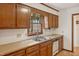 Well-lit kitchen sink area featuring wood cabinetry and a view of mature trees at 401 Joyce Rd, Hillsborough, NC 27278