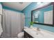 Bright bathroom featuring teal walls, a dark vanity, a large mirror, and a shower with a gray curtain at 4601 Timbermill Ct # 302, Raleigh, NC 27612