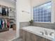 Bright bathroom boasting tiled bath and walk-in closet access at 904 Hidden Jewel Ln, Wake Forest, NC 27587