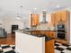Bright kitchen with stainless steel appliances, black countertops, and wooden cabinets at 904 Hidden Jewel Ln, Wake Forest, NC 27587