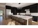 Modern kitchen with sleek black cabinetry, waterfall island, stainless steel appliances, and marble backsplash at 95 Cherry Bark Dr, Youngsville, NC 27596