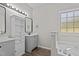 Bathroom featuring double vanities, and a soaking tub below a bright window at 112 Roping Horn Way, Willow Springs, NC 27592