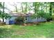 The rear view of a blue gray brick home showcases the peaceful, green backyard and natural surroundings at 1212 St. Marys Rd, Hillsborough, NC 27278