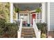 Inviting covered front porch with red door, hanging ferns, seating, and freshly painted railing at 1300 Marshall Farm St, Wake Forest, NC 27587