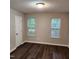 A bright, neutral bedroom with two windows, white door and wood-look flooring at 132 Waiters Way Way, Youngsville, NC 27596