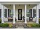 Inviting front porch with stone floor, seating, and decorative wreath on the glass front door at 1332 Gloriosa St, Apex, NC 27523