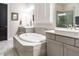 Bright bathroom featuring a soaking tub with gray tile surround, double vanity and plantation shutters at 136 Glenpark Pl, Cary, NC 27511