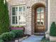 Arched, wooden front door of home with brick facade, sidelight, and a windowbox with colorful flowers at 136 Glenpark Pl, Cary, NC 27511