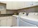 Well-lit laundry room featuring white cabinets, granite countertops, and modern appliances at 136 Glenpark Pl, Cary, NC 27511