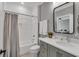 Well-lit bathroom featuring a vanity, decorative mirror, and a shower with gray and white tile at 1801 Clifton Pines Dr, Cary, NC 27519