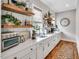 Functional butler's pantry with white cabinets, quartz countertops, floating shelves, and hardwood floors at 1801 Clifton Pines Dr, Cary, NC 27519