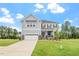 Beautiful home exterior featuring a manicured lawn, stone accents, two-car garage, and classic gray siding under a blue sky at 20 Bold Dr, Youngsville, NC 27596