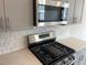 Close up on the gas range, microwave, and quartz countertops with tiled backsplash in a modern kitchen at 3007 Honeymyrtle Ln, Durham, NC 27703