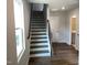 Open staircase with wood treads, iron railings, and natural light from a nearby window at 3007 Honeymyrtle Ln, Durham, NC 27703