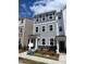 Charming three-story townhouse with gray siding, stone accents, and manicured landscaping under a sunny, partly cloudy sky at 3012 Honeymyrtle Ln, Durham, NC 27703
