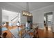 Sunlit dining area showcasing a glass table, modern light fixture, hardwood floors, and views of staircase at 3416 Cottonwood Dr, Durham, NC 27707