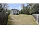 Large backyard featuring a gray home, lawn, and partial fence surround at 404 Braxman Ln, Holly Springs, NC 27540