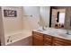 Bright bathroom featuring double sink vanity, soaking tub, and view of a bedroom in the mirror at 404 Braxman Ln, Holly Springs, NC 27540