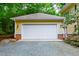 View of the detached, two-car garage featuring a white door and yellow siding with brick foundation at 407A Hillsborough St, Chapel Hill, NC 27514