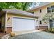 View of the detached, two-car garage featuring a white door and yellow siding with brick foundation at 407A Hillsborough St, Chapel Hill, NC 27514