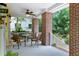 Cozy porch with ceiling fan, brick columns, outdoor seating, and a view of green trees at 407A Hillsborough St, Chapel Hill, NC 27514