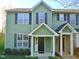 Charming two-story townhome featuring green siding, black shutters, and a welcoming covered front porch at 4425 Moss Garden Path, Raleigh, NC 27616
