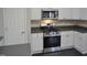 Modern kitchen featuring white cabinets, dark countertops, and stainless-steel appliances at 4425 Moss Garden Path, Raleigh, NC 27616