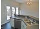 Bright kitchen features stainless steel dishwasher, double basin sink, white cabinets and tiled floors at 4425 Moss Garden Path, Raleigh, NC 27616