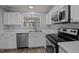 Bright kitchen with white cabinets, stainless steel appliances, and view into living area at 4447 Antique Ln, Raleigh, NC 27616