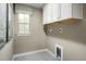 Compact laundry room with ample cabinet space and natural light from a window at 557 Freedom Trail Dr, Willow Springs, NC 27592