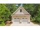A two-car garage with a peaked roof, complemented by tan siding and surrounded by lush greenery at 63 Tally Ho Dr, Selma, NC 27576
