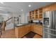 Bright kitchen with wood cabinets, stainless fridge, bar counter top, and tile floors, open to stairway at 63 Tally Ho Dr, Selma, NC 27576