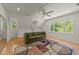 Bright living room features a large window, plush sofa, ceiling fan, and colorful area rug at 63 Tally Ho Dr, Selma, NC 27576
