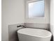 Elegant soaking tub with modern fixtures and tiled surround, bathed in natural light at 7950 Country Knoll Rd, Bahama, NC 27503