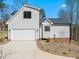 View of the side of the home featuring a two-car garage, light gray siding, black trim, and concrete driveway at 7950 Country Knoll Rd, Bahama, NC 27503