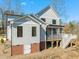 View of the rear of the house with light gray siding, black trim, screened porch and a full basement entrance at 7950 Country Knoll Rd, Bahama, NC 27503