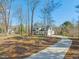 Beautiful two-story home featuring white siding and a long, winding driveway surrounded by lush trees at 7950 Country Knoll Rd, Bahama, NC 27503