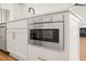 Kitchen island features stainless microwave, white cabinets and drawers with gold hardware at 7950 Country Knoll Rd, Bahama, NC 27503