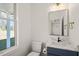 Elegant powder room featuring marble countertop, navy vanity, and stylish mirror with lights at 7950 Country Knoll Rd, Bahama, NC 27503