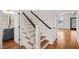 Stylish staircase with wood treads, white risers, and black handrail at 7950 Country Knoll Rd, Bahama, NC 27503
