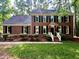 Charming brick home featuring black shutters, a manicured lawn, and mature trees, creating a welcoming curb appeal at 100 Lochberry Ln, Cary, NC 27518