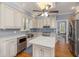 Bright kitchen with white cabinets, stainless steel appliances and an island with a marble countertop at 100 Lochberry Ln, Cary, NC 27518
