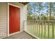 Exterior view of a balcony with a red door and white railings, offering a glimpse of the trees at 1300 Hillbrow Ln # 204, Raleigh, NC 27615