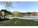 Scenic pond view showcasing lush landscaping, a paved walking path, and mature trees under a clear blue sky at 200 Nottinghill Walk, Apex, NC 27502