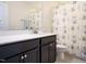 Bathroom with a dark vanity, white countertop, decorative mirror, and patterned shower curtain at 2217 Magnolia Tree Ln, Durham, NC 27703
