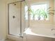 Bright bathroom featuring a separate shower and tub beneath a sunny window with plants at 2217 Magnolia Tree Ln, Durham, NC 27703