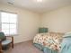 Carpeted bedroom with a patterned bedspread, a window providing natural light, and a small dresser at 2217 Magnolia Tree Ln, Durham, NC 27703