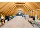 Large attic area offers ample storage with wooden beams, flooring, and a small window at the end at 2223 Winston Cir, Apex, NC 27502