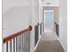 Second floor hallway featuring wood and wrought iron railing, carpet flooring, and bedroom view at 286 Sea Mist Dr, Sanford, NC 27332